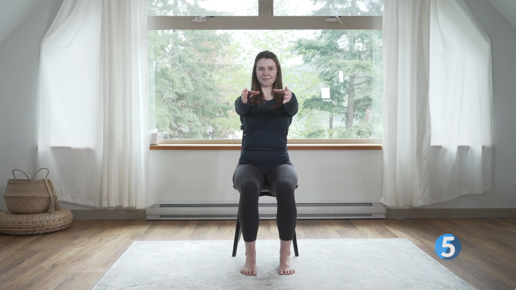 With her arms out in front of her and feet planted on the floor, the instructor is ready to take on her next seated leg exercise