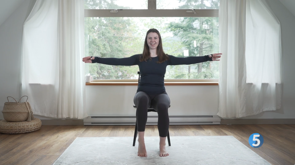 The instructor raises her arms out to her sides and presses through her toes on one foot utilizing seated leg exercises to help her strengthen her legs
