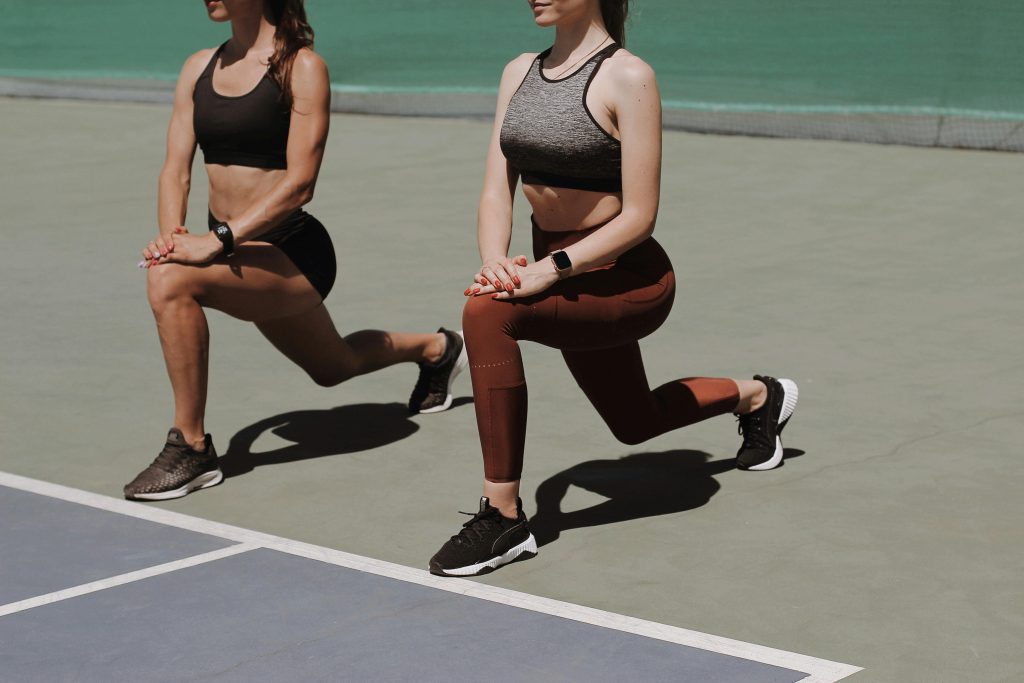 Two ladies performing lunges outdoors 