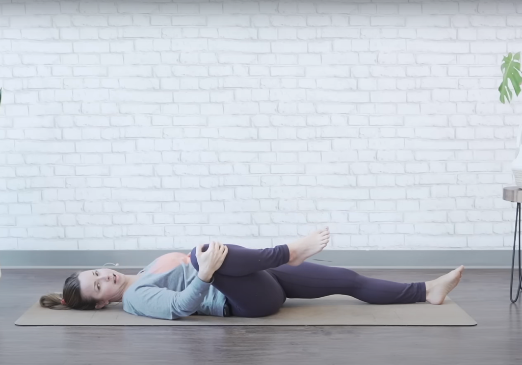 Demonstrating the single knee-to-chest bed exercise - ending position