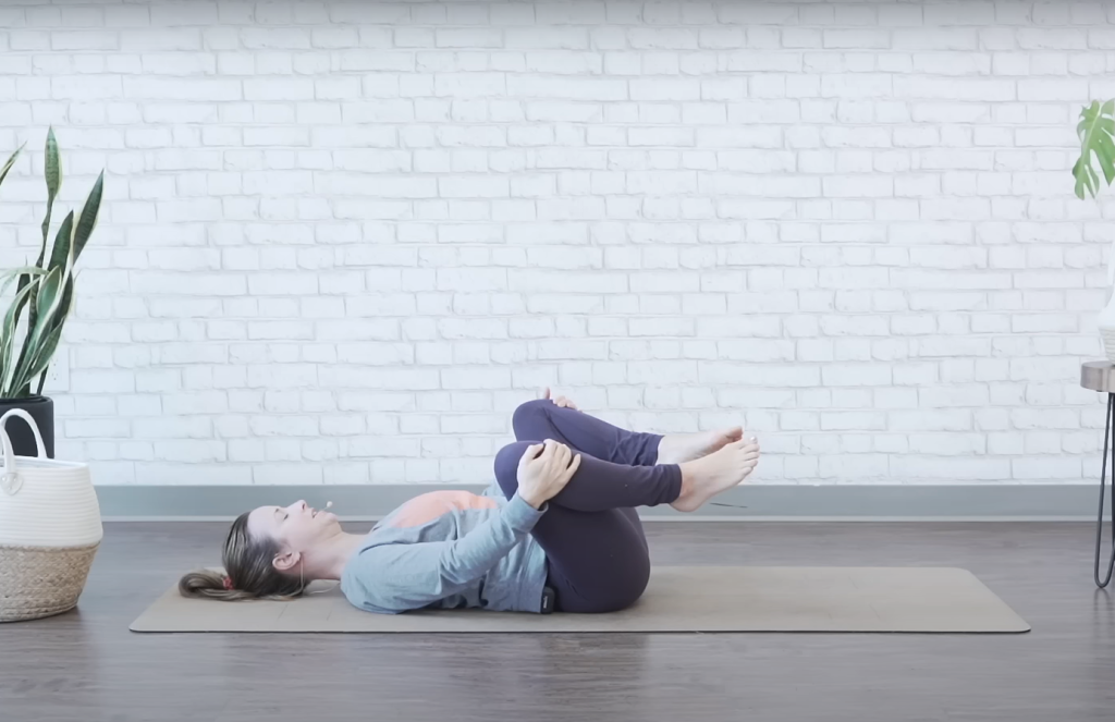 Demonstrating the knee-to-chest bed exercise - ending position