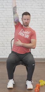 Fitness instructor performs one of the best arm exercises for seniors, a seated overhead shoulder press using one arm.
