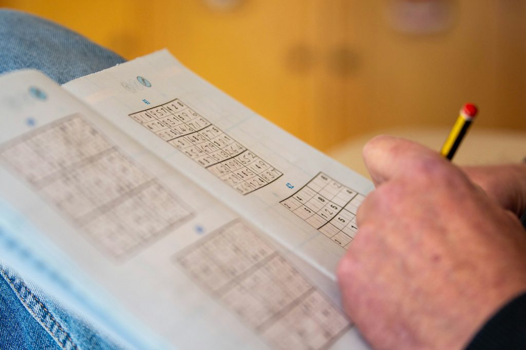 A senior solving a Sudoku puzzle, which is among the most popular memory games for seniors.