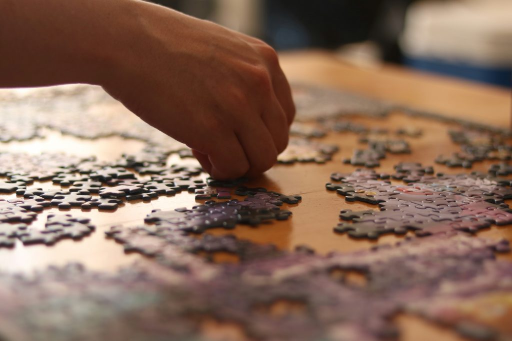 A senior working on a jigsaw puzzle, one of the popular memory games for seniors, carefully placing a piece onto the puzzle board.