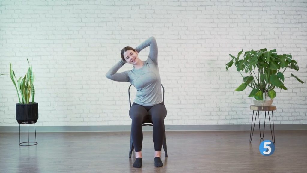 Female instructor demonstrating a seated core strengthening exercise engaging the abdominal muscles