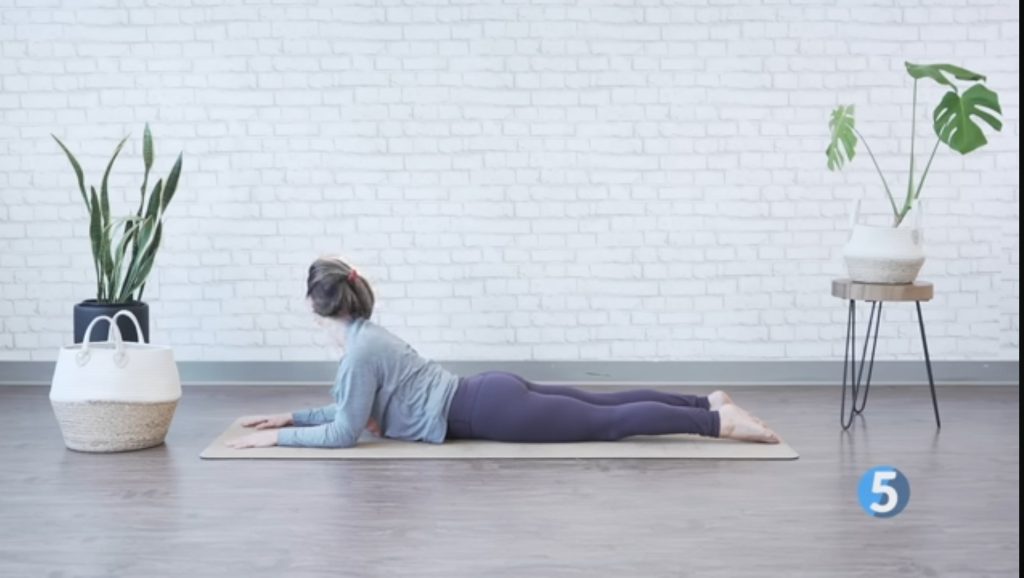 A woman performing sphinx pose in a morning stretch routine for seniors.