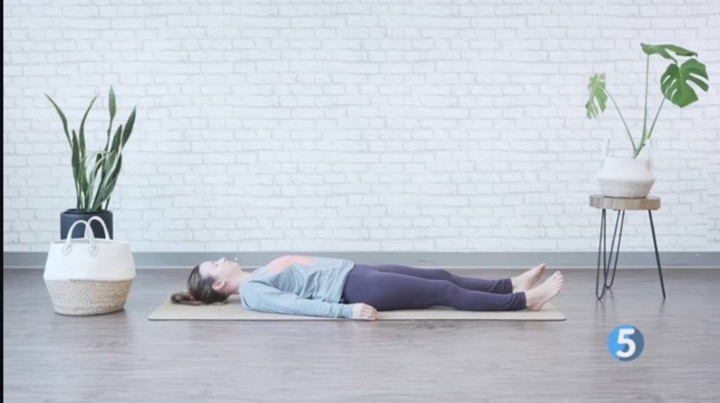 A woman in Shavasana, relaxing as part of a morning stretch routine for seniors.