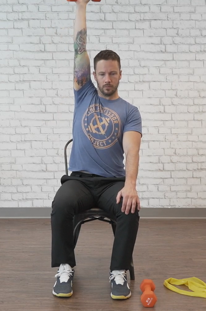 A man demonstrates a seated dumbbell press, one of the movements included in the seated exercises for seniors PDF.