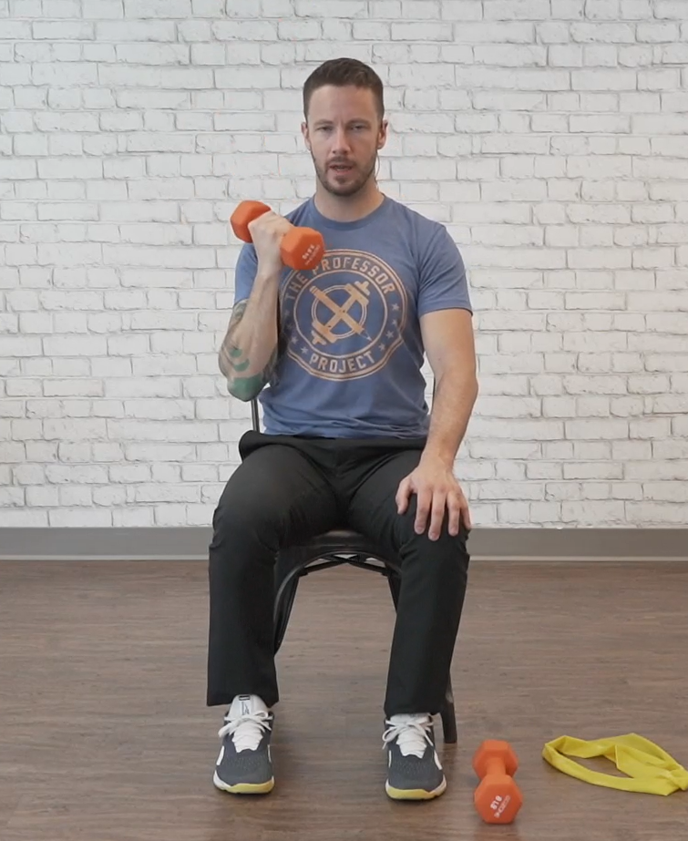 A man holds a dumbbell at shoulder height in the starting position for a dumbbell press