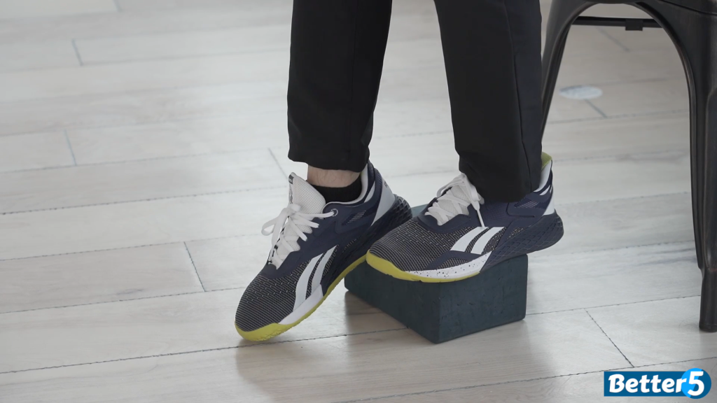The fitness instructor works on his ankle mobility with this exercise, by placing his heel on the yoga block and pointing his toes to the ground.