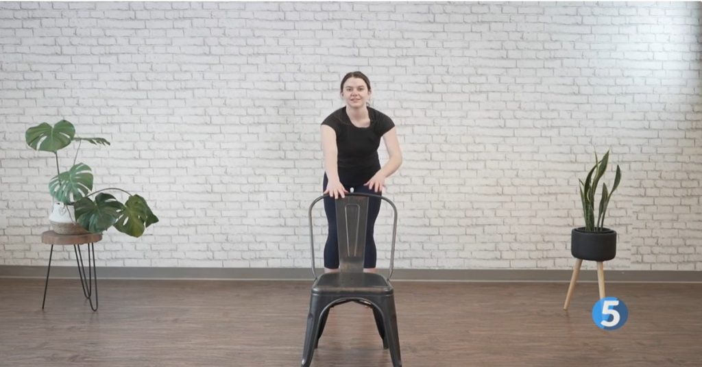 instructor doing standing hip exercises with chair support