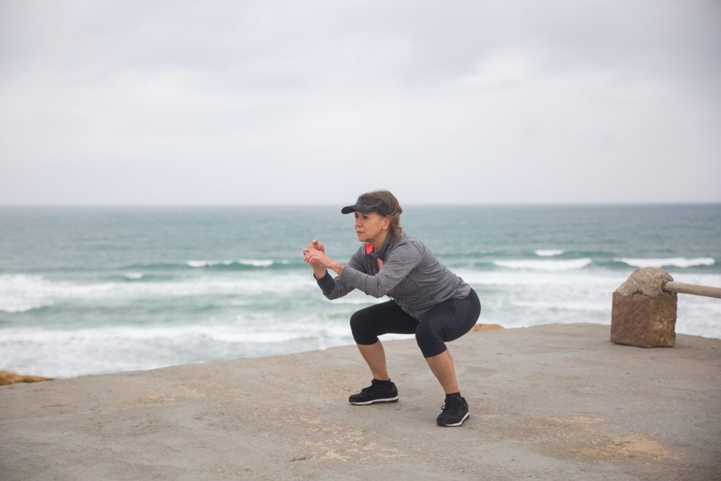 senior woman doing squat exercise to strengthen knee joints & muscles