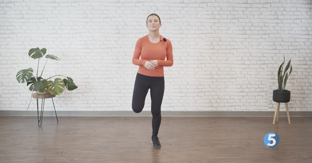 Instructor doing a standing low-impact workout at home for older adults