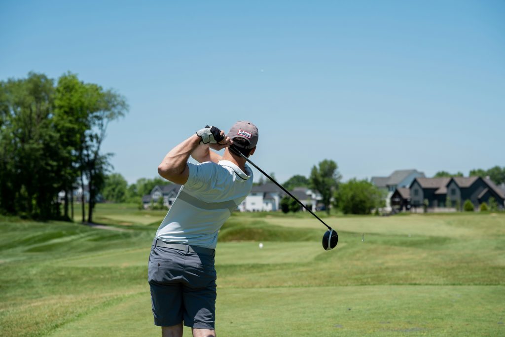 A man swings a golf club creating a twist that makes golfing one of the osteoporosis exercises to avoid.