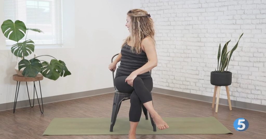 Instructor doing seated chair yoga twist exercise for mobility
