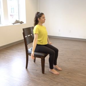 A fitness instructor demonstrates the starting position of lateral arm raises.