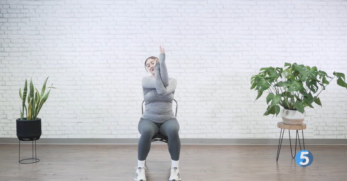 instructor performing a gentle seated stretch for older adults