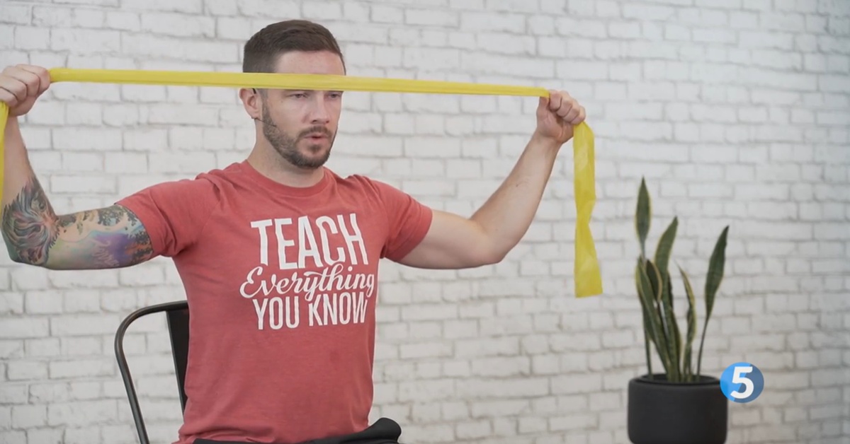 instructor performing seated arm stretch excercise for seniors