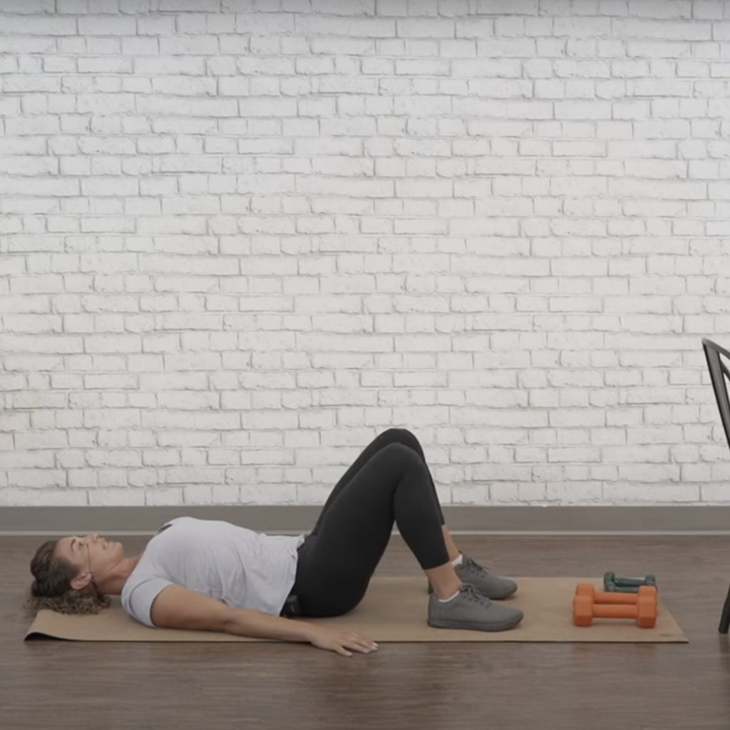 Woman demonstrates how to start glute bridges exercise for seniors