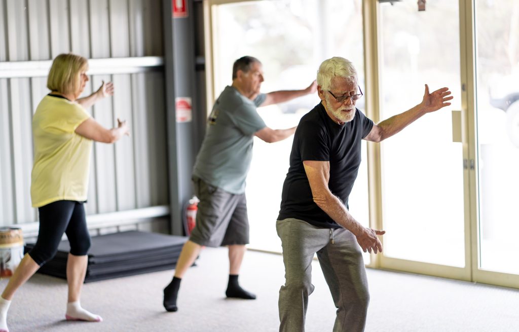 A group of seniors get together regularly at their Tai Chi class so they can go through the exercises together and get the support they need to keep them coming back.