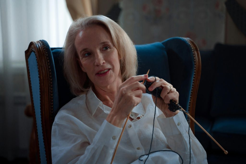 Blonde elderly lady cheerfully knitting in a serene setting, enjoying what many consider the best hobby for senior women.