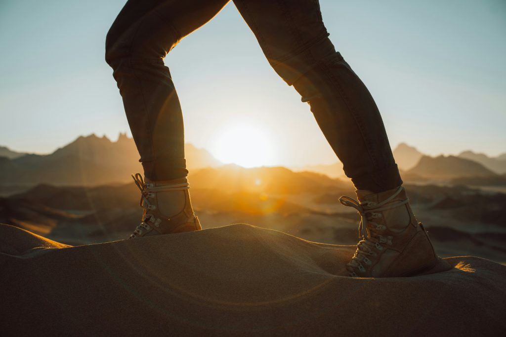Hiking boots on sand dunes at sunset, showing that hiking for seniors can be adventurous.